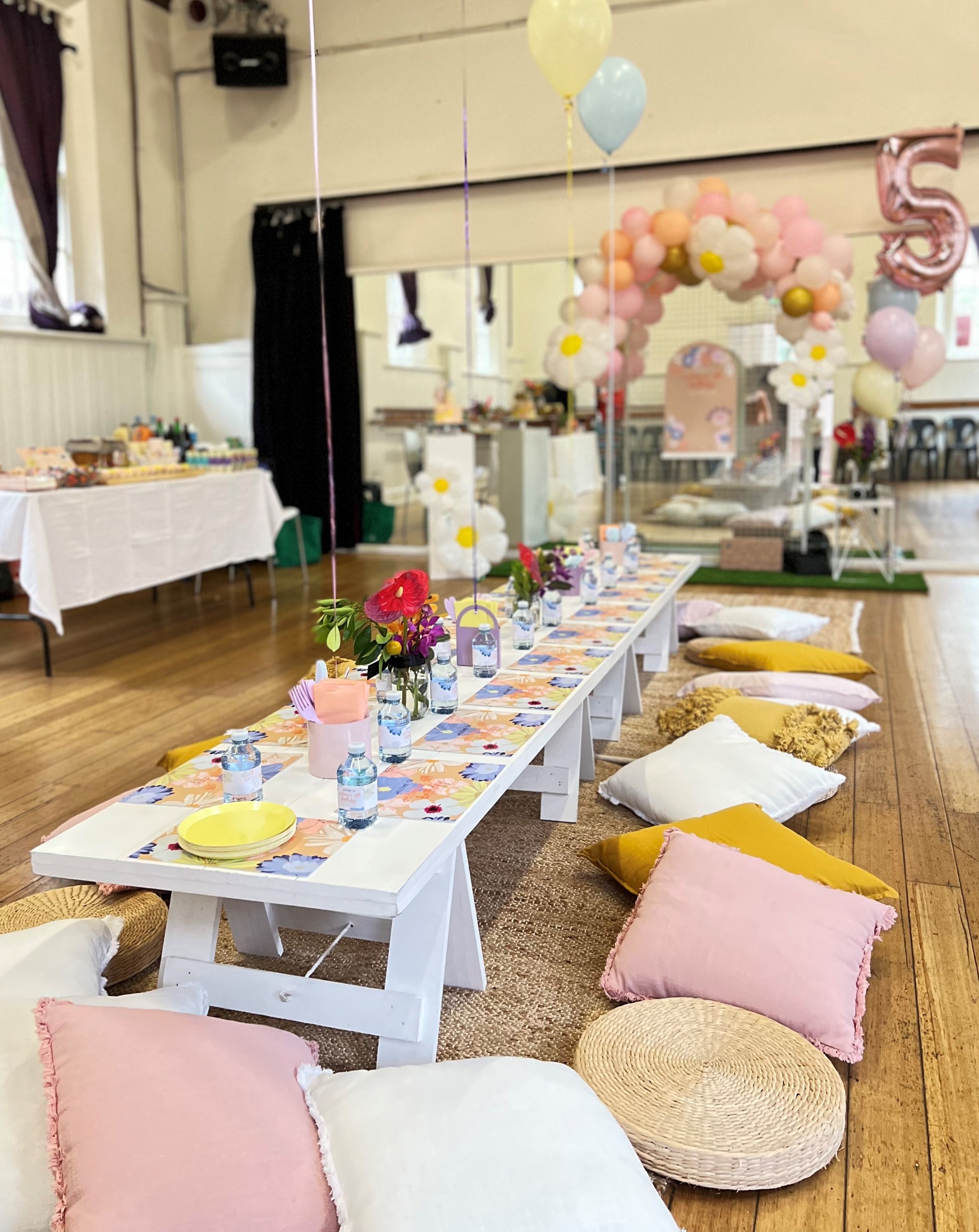 Interior of hall with table and cushions set up for child's 5th birthday party