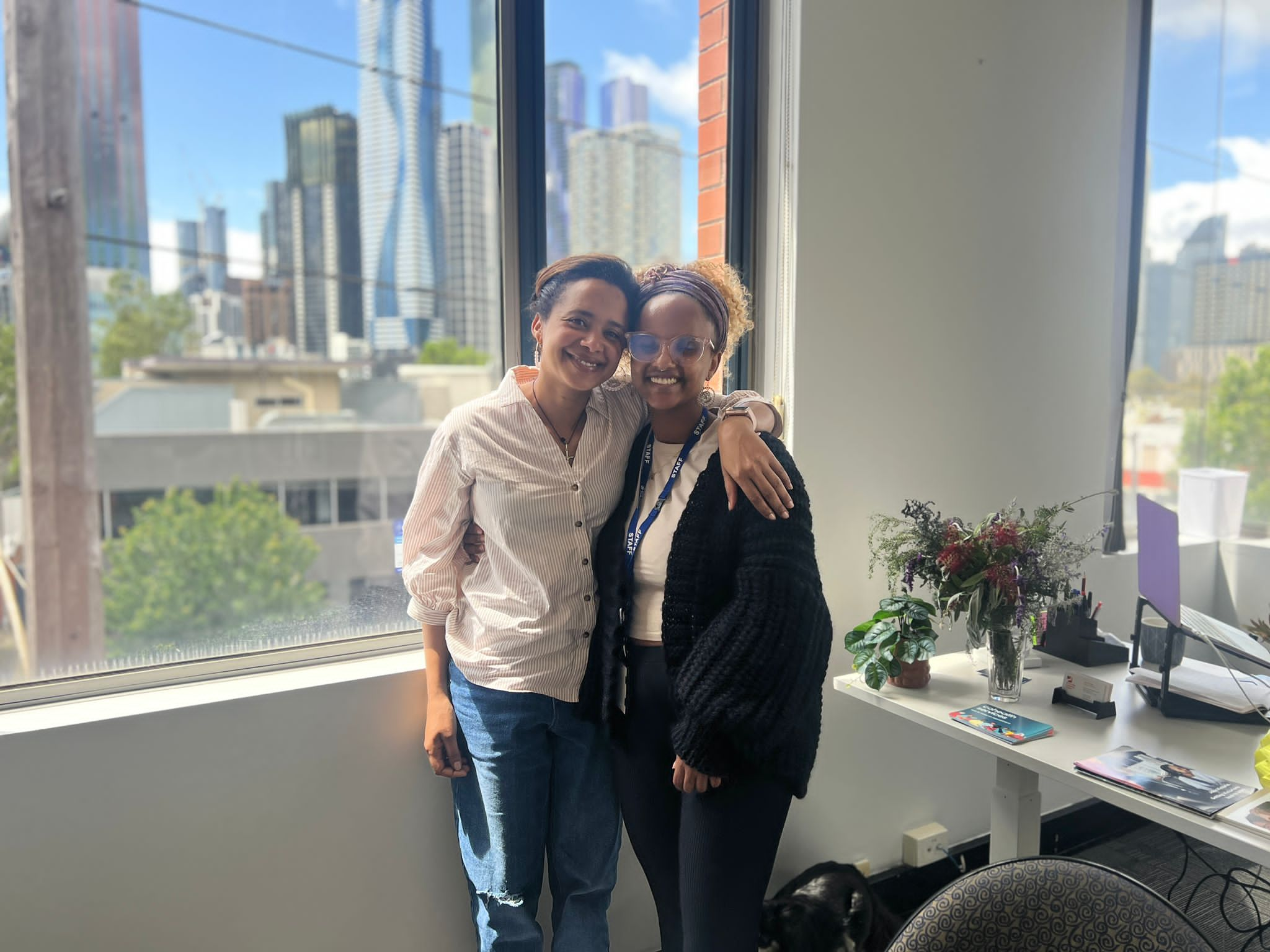 Two women in embrace smile at camera