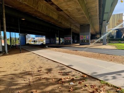 A road and path with a freeway bridge above it. 