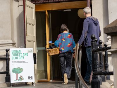 A photo of participants arriving at the workshop with an Urban Forest and Ecology A frame sign. 